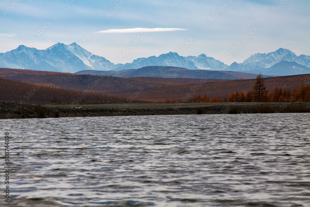 Snowy peaks of Eastern Sayan mountains in autumn with water of a lake in front Snowy peaks of Eastern Sayan mountains in autumn with water of a lake in front