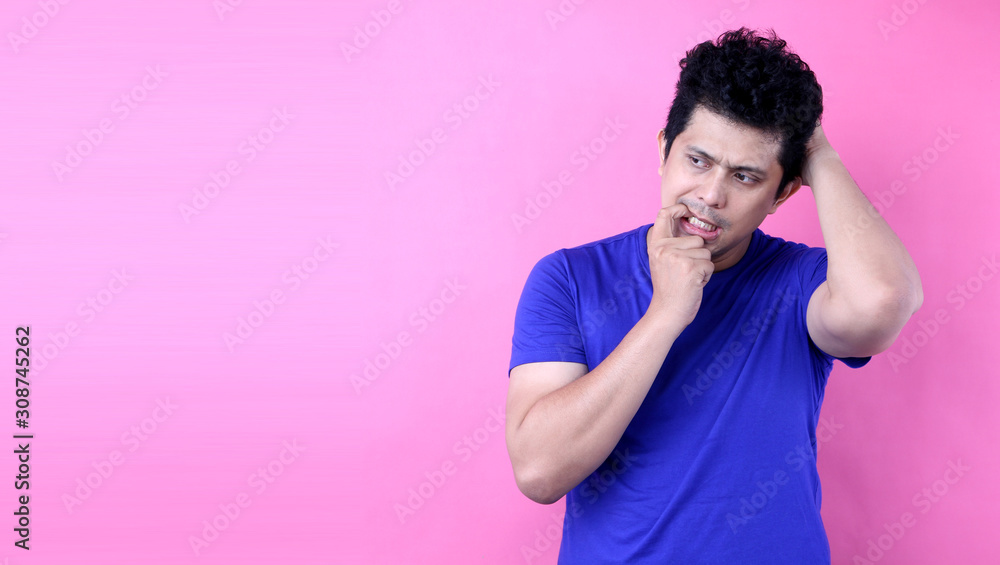 Portrait Young Asia man having doubts and with confuse face expression on pink background in studio With copy space. Portrait Young Asia man having doubts and with confuse face expression on pink background in studio With copy space.