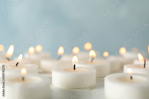 Group of burning candles against blue background, close up