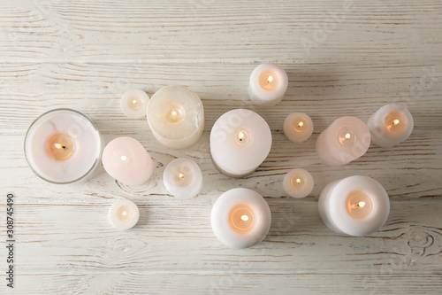 Obraz na płótnie Different burning candles on wooden background, top view
