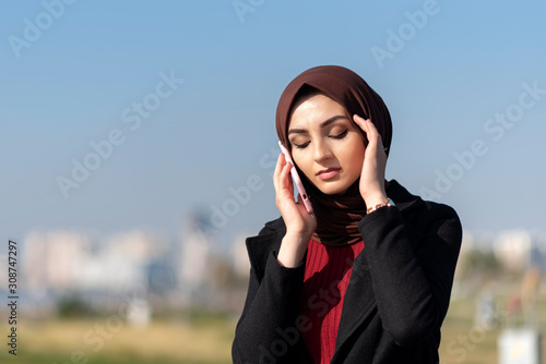 sad muslim young woman talking by phone