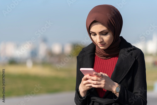 muslim young woman typing message with her smartphone