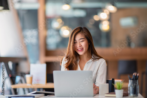 Portrait of young businesswoman watching at laptop and smiling 