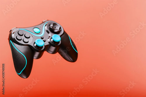 Black joystick game controller with blue levitation buttons isolated on pink background.