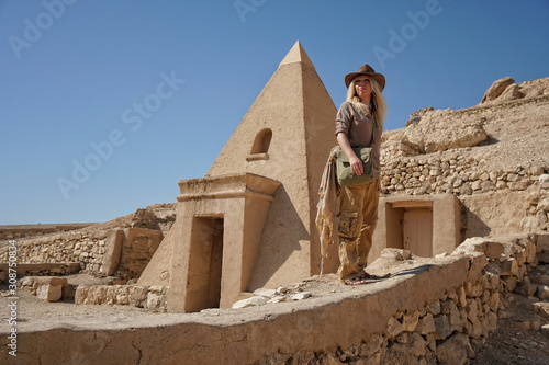 blonde Frau in outdoor Kleidung als Tourist auf Bildungsreise neben einer kleinen Pyramide in Luxor, Ägypten photo