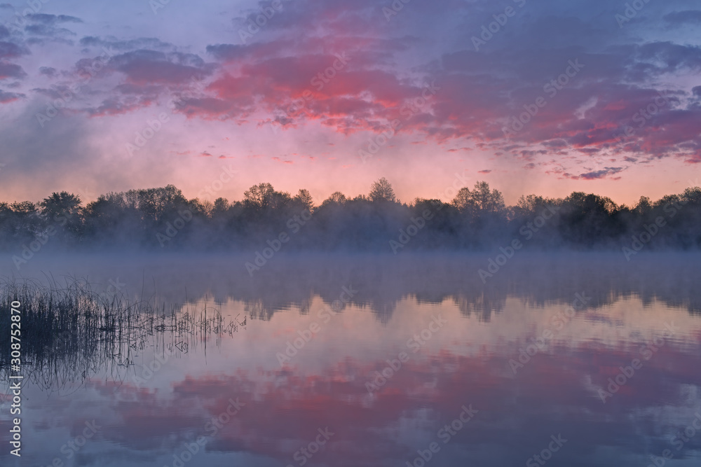 Foggy landscape at dawn of Whitford Lake with reflections in calm water, Fort Custer State Park, Michigan, USA