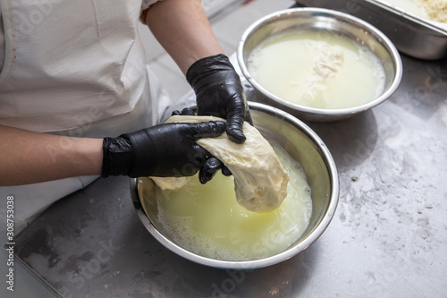 Italian hard cheese silano or caciocavallo in cheesemaker hands. The home-made cheese maker produces handmade caciocavallo. Concept: tradition, italy, mozzarella.The process of making mozzarella. photo