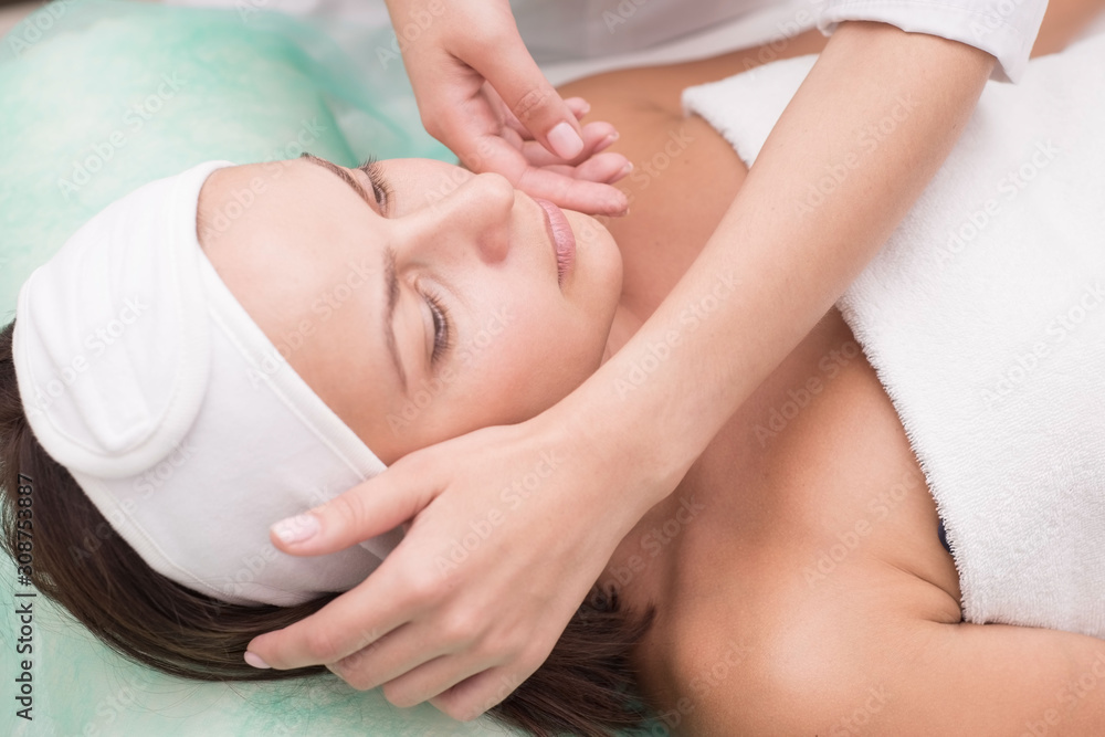 Girl massage therapist does facial massage with a beautiful woman. Hands are closing. Massage room Girl massage therapist does facial massage with a beautiful woman. Hands are closing. Massage room