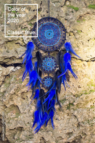 Handmade dream catcher with feathers threads and beads rope hanging in classic blue trendy color of the year 2020.