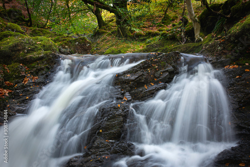 Tranquil autumn woodland scene with waterfall in Scottish highlands.Motion of flowing water.Fairytale nature scenery.