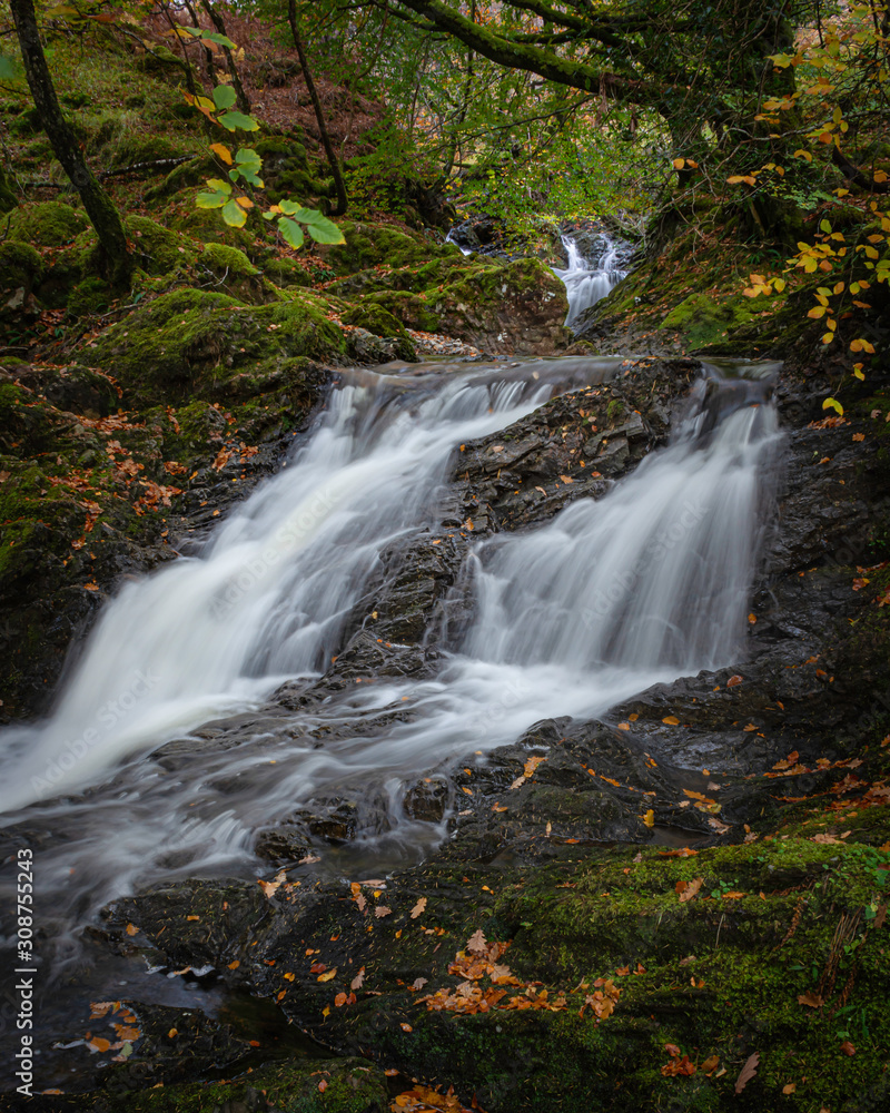 Tranquil autumn woodland scene with waterfall in Scottish highlands.Motion of flowing water.Fairytale forest scenery.Tranquil nature scene. Tranquil autumn woodland scene with waterfall in Scottish highlands.Motion of flowing water.Fairytale forest scenery.Tranquil nature scene.