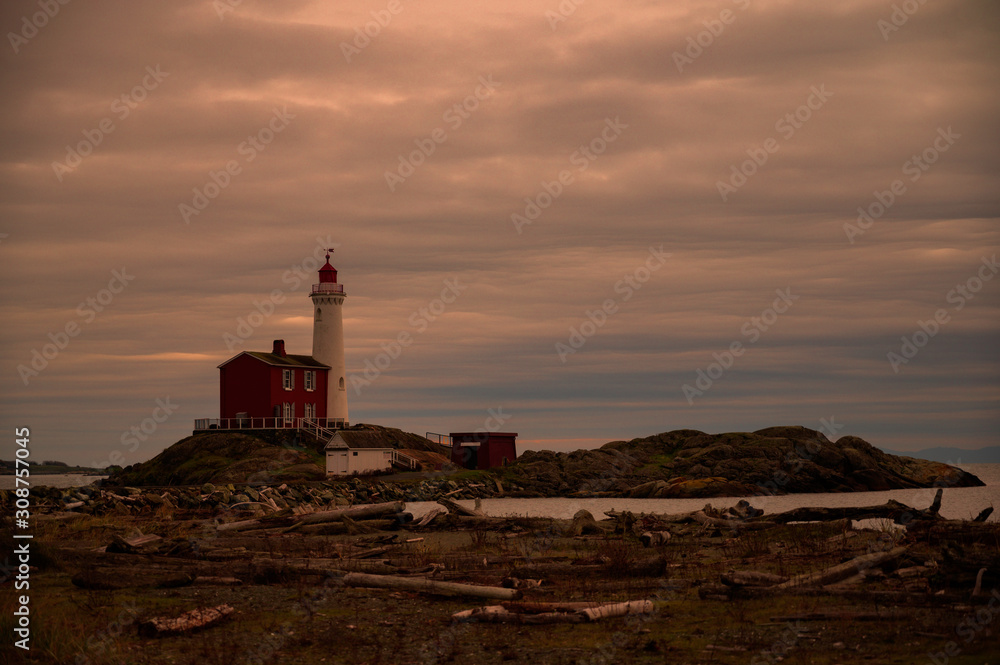 Stunning Lighthouse and Red Brick Building with Bay and Dramatic Clouds in Sky