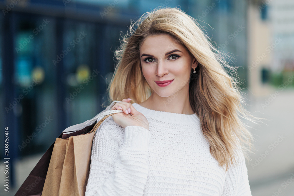 Young attractive pregnant blonde woman in a white sweater against the backdrop of the city streets. Holding a lot of shopping bags. Young attractive pregnant blonde woman in a white sweater against the backdrop of the city streets. Holding a lot of shopping bags.