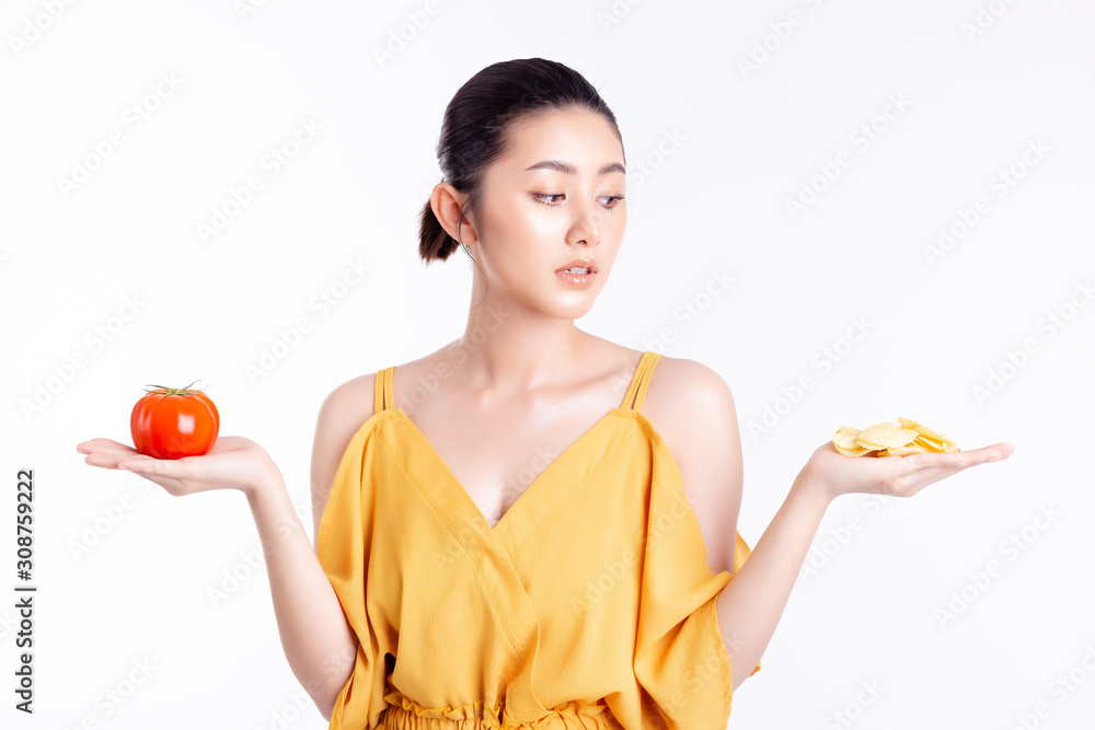 Diet concept. Beautiful young asian woman looks at delicious snack, potato chip. Attractive girl consider, restrain for stopping eat snack because she gets slimming plans. She hold tomato, potato chip Diet concept. Beautiful young asian woman looks at delicious snack, potato chip. Attractive girl consider, restrain for stopping eat snack because she gets slimming plans. She hold tomato, potato chip