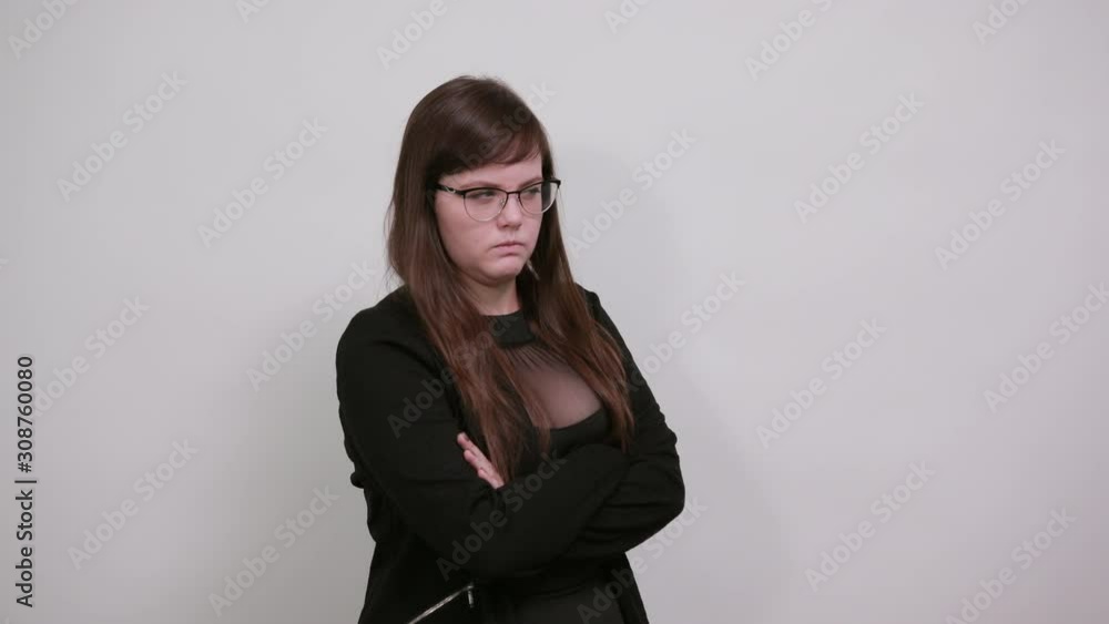 Smiling young woman in casual clothes holding hands crossed, looking angry isolated on gray wall background. People sincere emotions, lifestyle concept. Smiling young woman in casual clothes holding hands crossed, looking angry isolated on gray wall background. People sincere emotions, lifestyle concept.