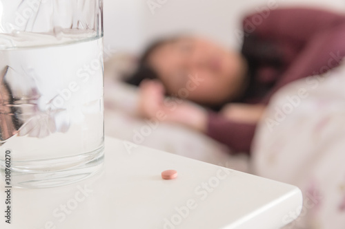Médicament avec un verre d'eau et une femme dormant en arrière plan photo