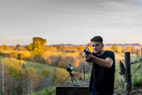 young caucasian man standing shooting pistol/handgun at outdoor gun range in Kentucky