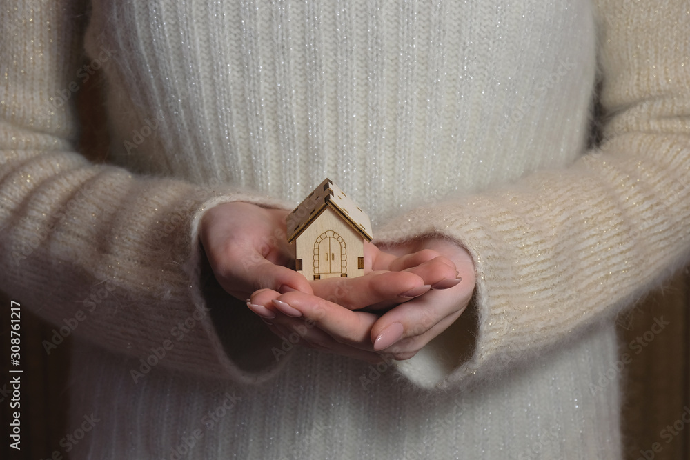 Fototapeta premium A small model of a wooden house stands on a hand. Concept image of my house. The project of a country house.