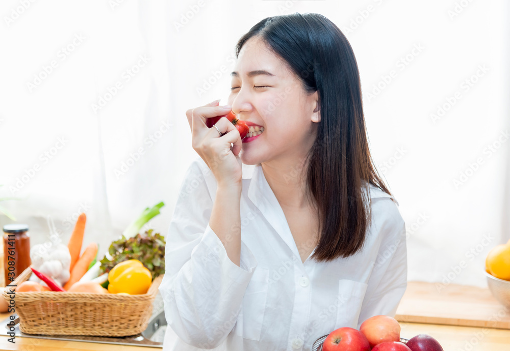 Happy young girl in kitchen enjoys eating red apples for healthy diet.Healthy eating and lifestyle concept. Happy young girl in kitchen enjoys eating red apples for healthy diet.Healthy eating and lifestyle concept.