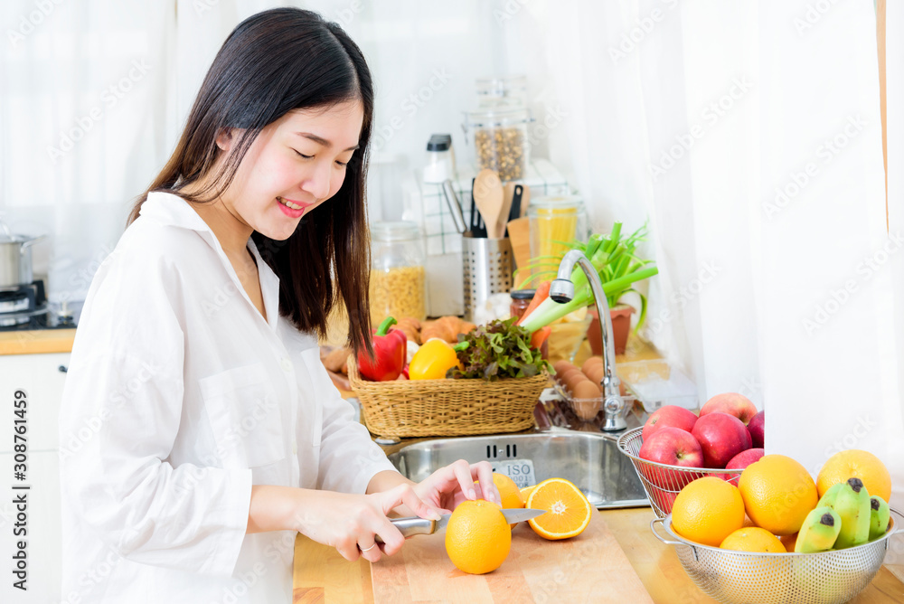 Happy young girl in kitchen cutting oranges in half for making fresh juice. Healthy eating and lifestyle concept. Happy young girl in kitchen cutting oranges in half for making fresh juice. Healthy eating and lifestyle concept.
