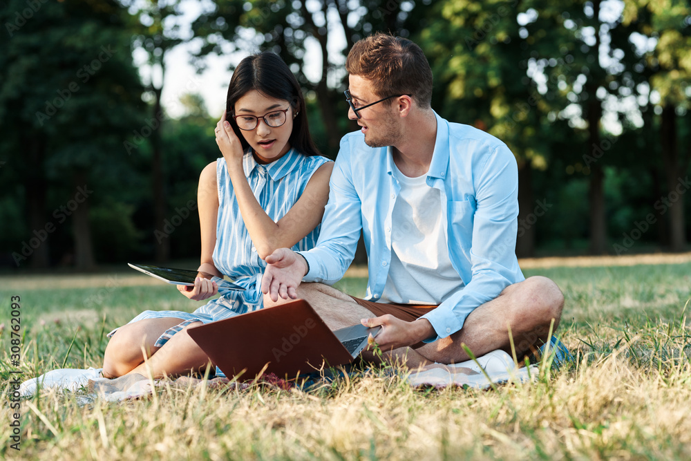young couple sitting on grass in park young couple sitting on grass in park