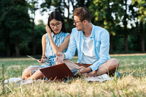 young couple sitting on grass in park