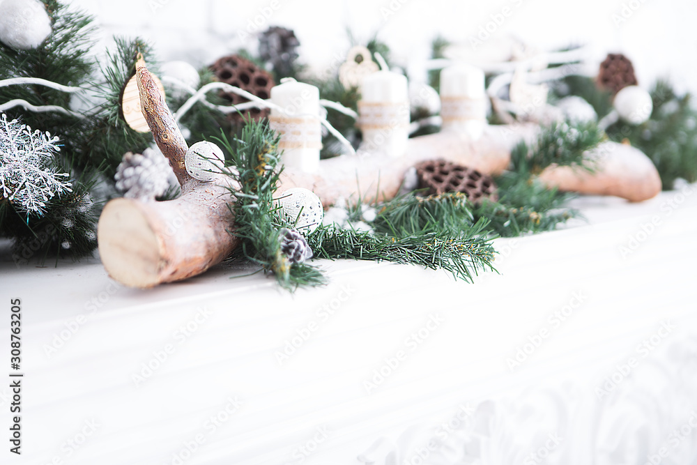 Christmas background with a decor of a shelf decorated with candles, branches of a Christmas tree, logs and Christmas toys