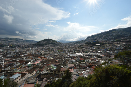 Colonial City of Quito, sunny afternoon on the tile roofs, several temples and ancient churches, in the background the monument to the Virgin on the hill called "Panecillo"