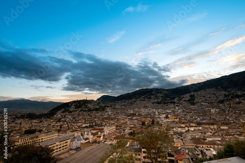 Colonial City of Quito, sunset over the tile roofs, several temples and ancient churches, in the background the monument to the Virgin on the hill called "Panecillo"