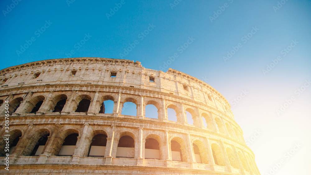 Colosseum or Coliseum ancient ruins background blue sky Rome, Italy, view from below, stone arches and sunrays