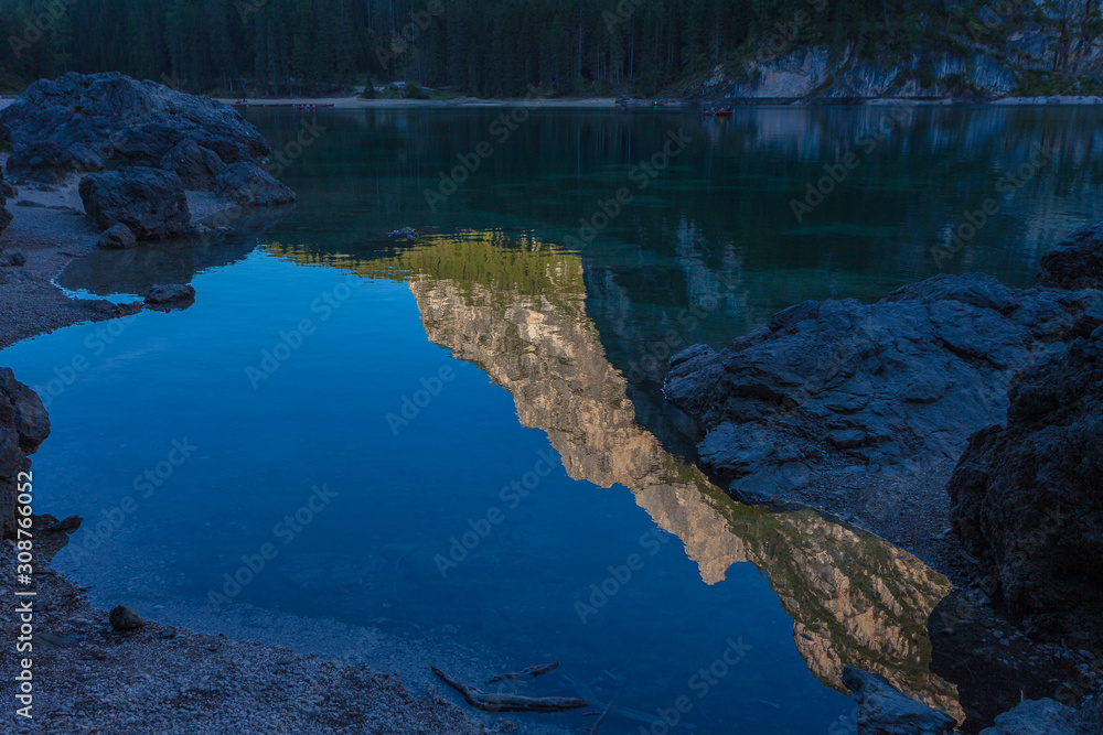 Dolomitic peaks and firs reflections on the Braies lake crystalline waters, South Tyrol, Italy. Concept: relaxation in nature, famous natural places, film sets