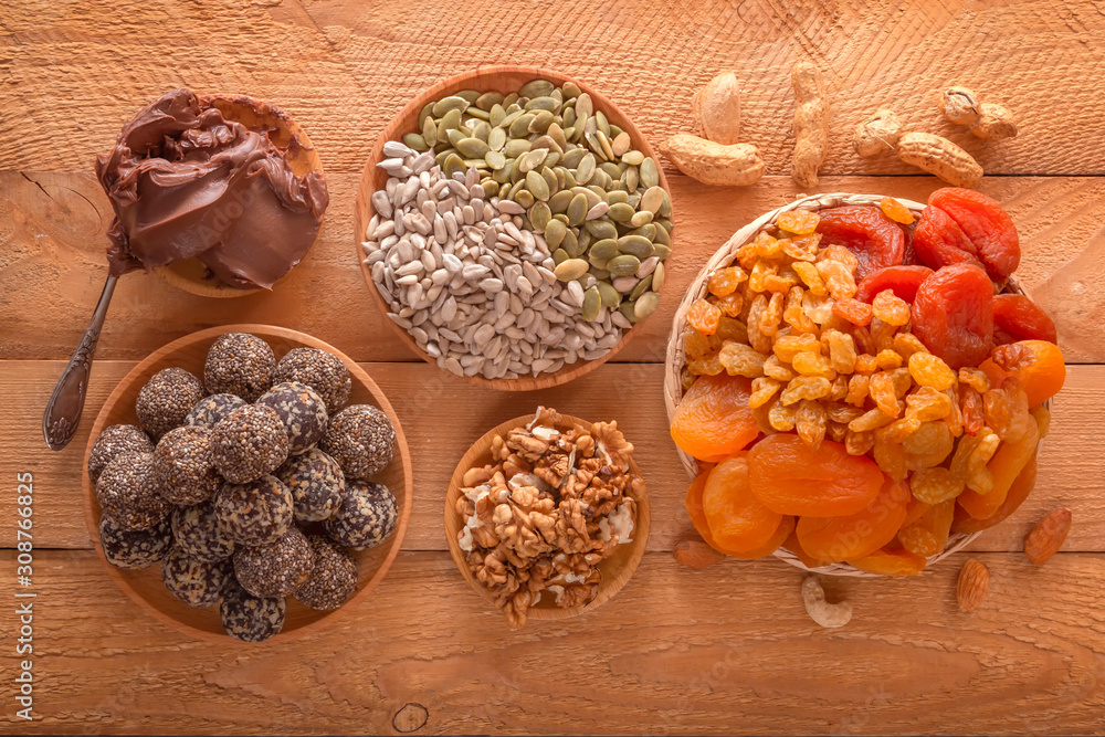 Natural healthy raw energy bites, chocolate paste and mix of dried fruits with nuts on a wooden table. Top view Natural healthy raw energy bites, chocolate paste and mix of dried fruits with nuts on a wooden table. Top view