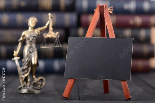 Fotografía Lady Justice and mini Blackboard on wooden background in front of law books libr