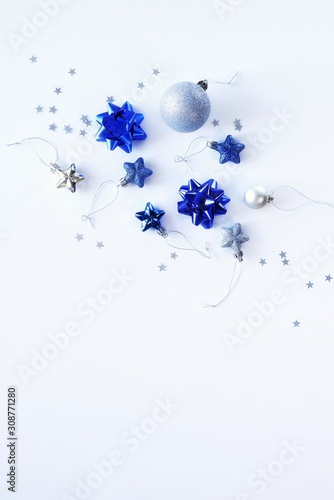 Creative mockup of Christmas decorations, stars and holiday bows. Classic blue colors on a white background. Christmas, New Year, happy holiday concept. Top view, flat lay with copy space for text.