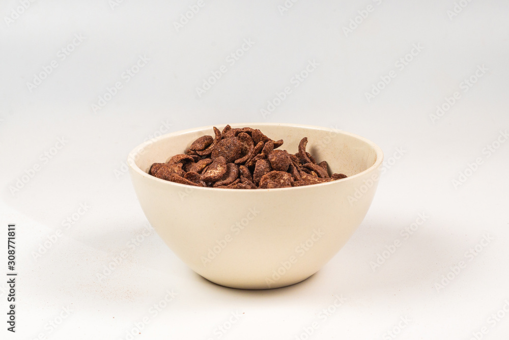 Chocolate corn flakes falling to the white bowl isolated on white. Motion. Chocolate corn flakes falling to the white bowl isolated on white. Motion.