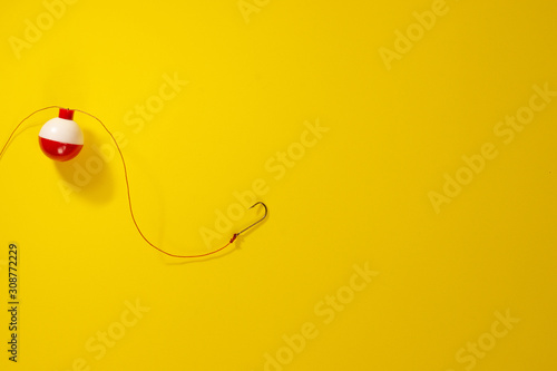 Photos fishing buoy and hook on a yellow background copy space..