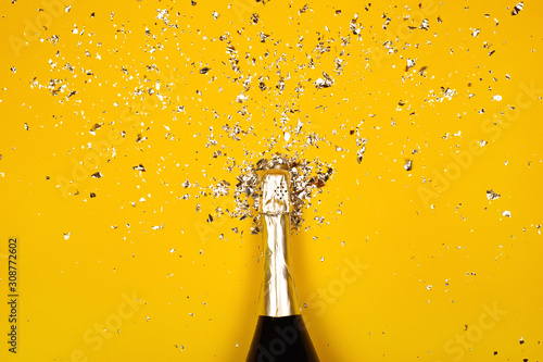 Canvas Bottle of champagne with splash of confetti. Flat lay style.