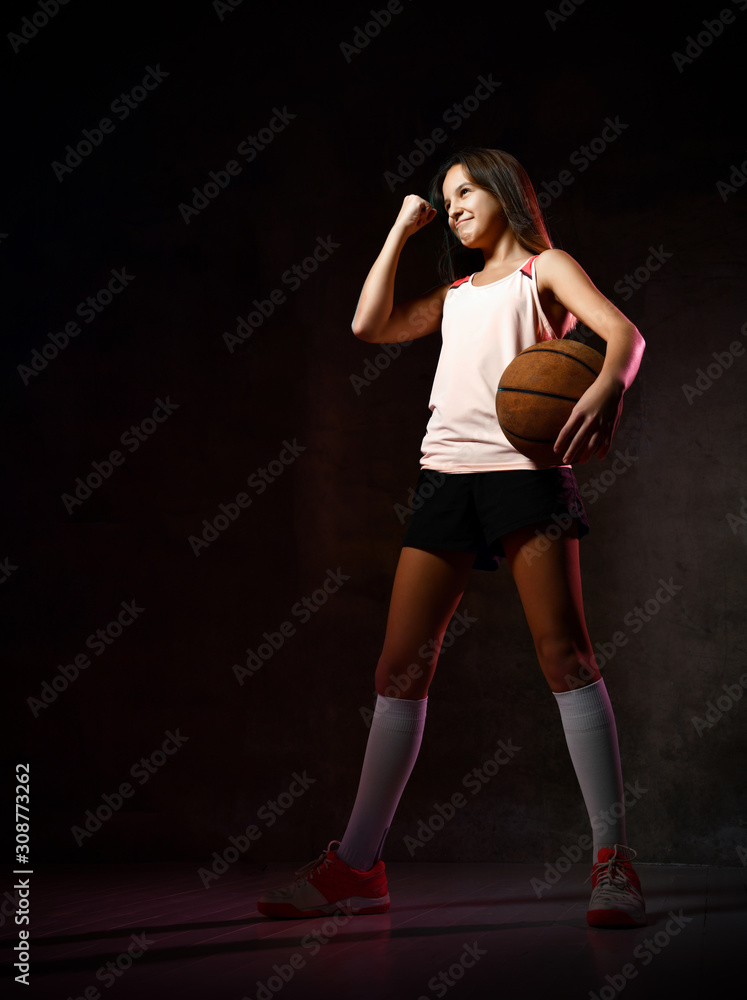 Beautiful caucasian teen woman in sportswear playing basketball . Sport concept isolated on black background. Beautiful caucasian teen woman in sportswear playing basketball . Sport concept isolated on black background.