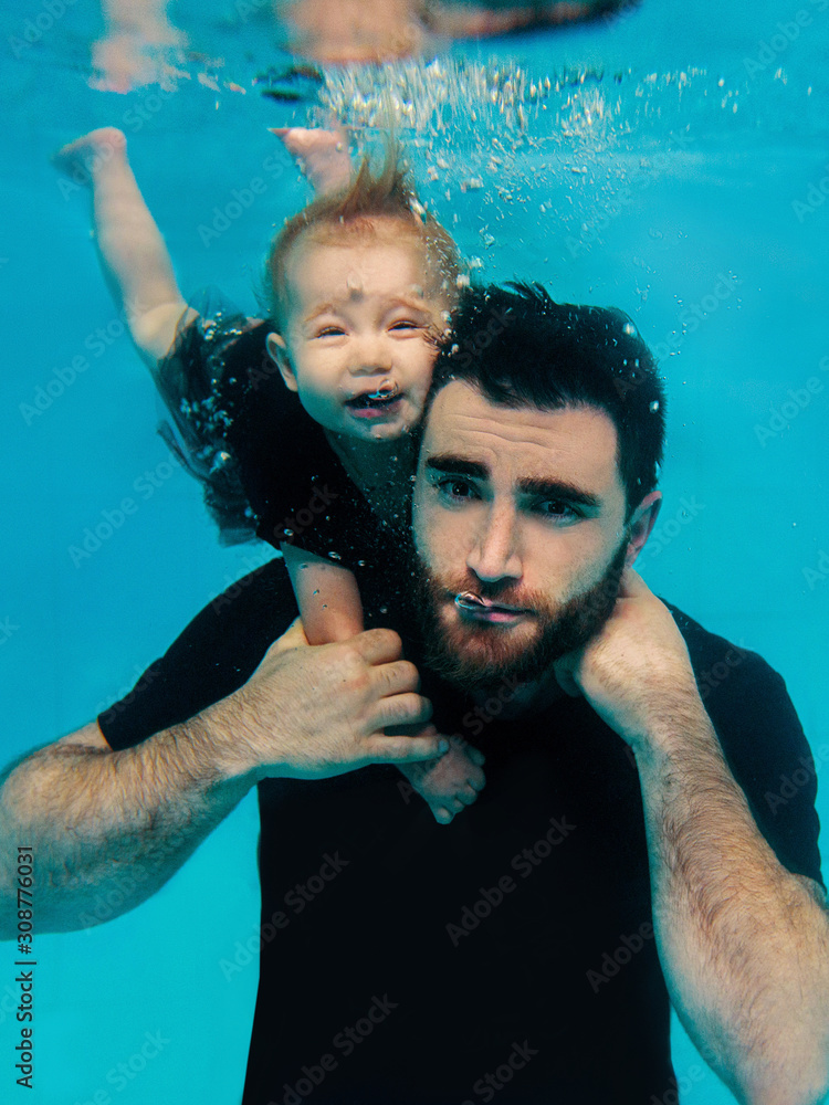 handsome cheerful father teaching his little daughter to dive underwater in the swimming pool. Family, lesson, holidays concept. 