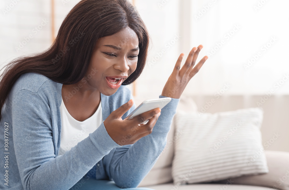 Portrait of young black woman shouting at mobile phone at home Portrait of young black woman shouting at mobile phone at home