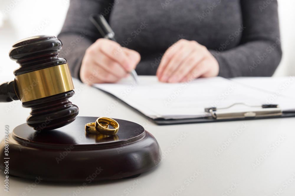 Hands of wife, husband signing decree of divorce, dissolution, canceling marriage, legal separation documents, filing divorce papers or premarital agreement prepared by lawyer. Wedding ring Hands of wife, husband signing decree of divorce, dissolution, canceling marriage, legal separation documents, filing divorce papers or premarital agreement prepared by lawyer. Wedding ring