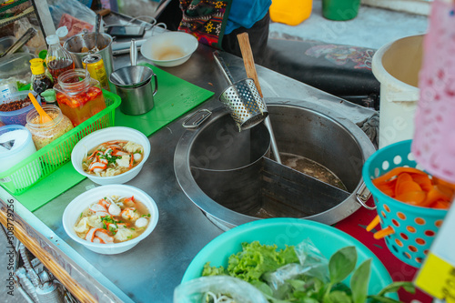 Street kitchen Pork soup with with noodles and herbs in Asia