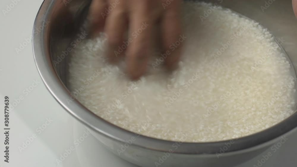 Making Japanese sushi rice, hand washing rice in metal bowl Making Japanese sushi rice, hand washing rice in metal bowl