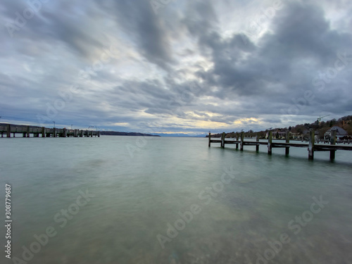 Pier with calm lake "Starnberger See" in Bavaria with smooth cloudy sky © Peter Maszlen