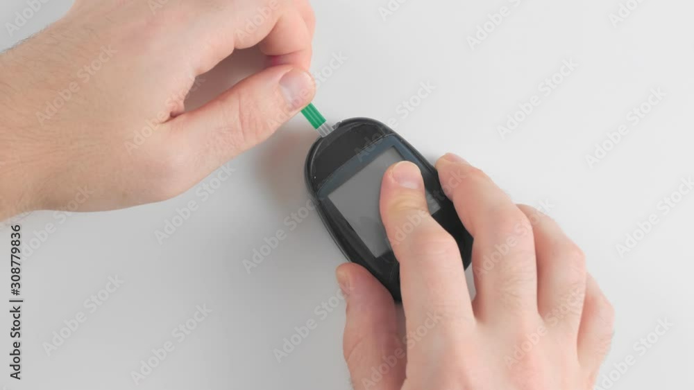 Unrecognized man prepares a glucose meter to measure blood glucose, sugar levels, for
