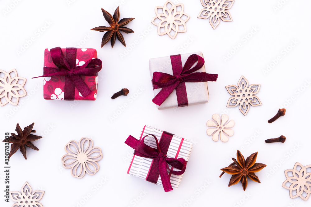 Christmas still life on white background. Three gifts in red, white and grey colors, dried cloves, star anise and wooden figures that looks like snowflakes or ice crystals. Old scandinavian style. Christmas still life on white background. Three gifts in red, white and grey colors, dried cloves, star anise and wooden figures that looks like snowflakes or ice crystals. Old scandinavian style.
