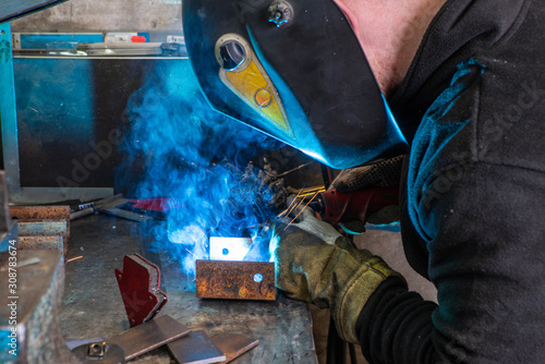 Worker in welding mask at factory. Welding process. Electric welding. Bright blue. © Aleks Kend
