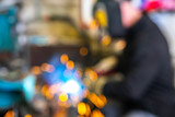 Blurred picture of worker in welding mask at factory. Welding process. Electric welding. Bright yellow sparks.
