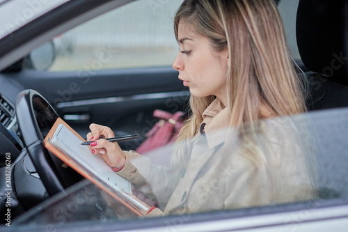 business woman in the car writing down a reminder on her agenda