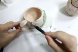 Person painting clay cup